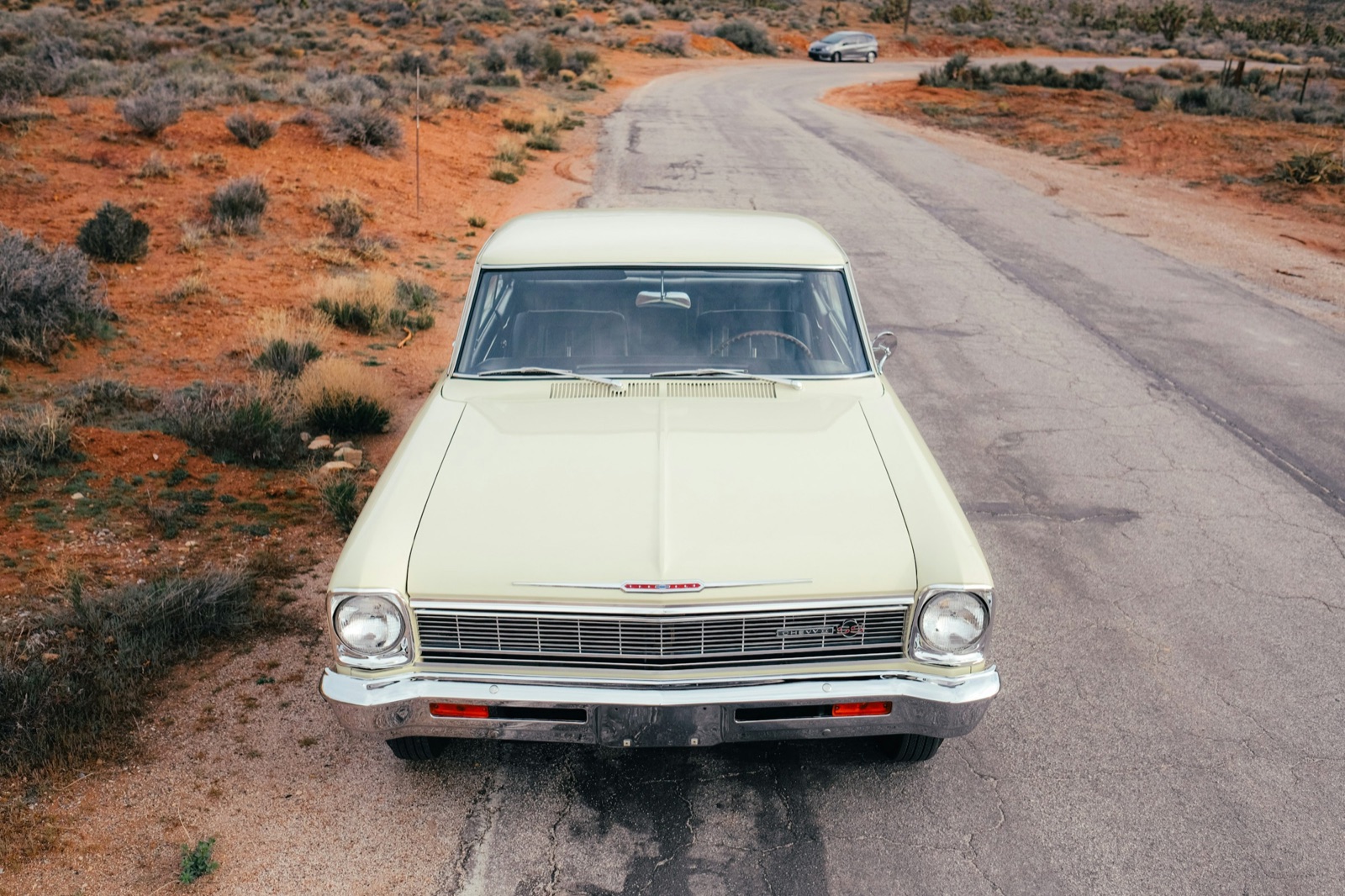 Cream 1960s coupe seen from the front on a desert road