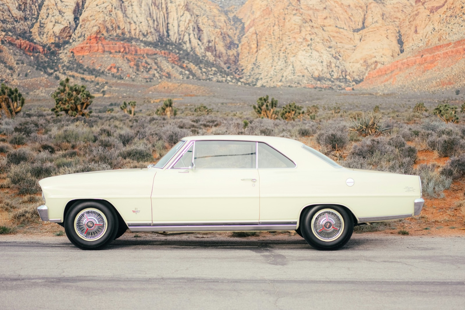 Cream 1960s coupe in side profile on a desert road
